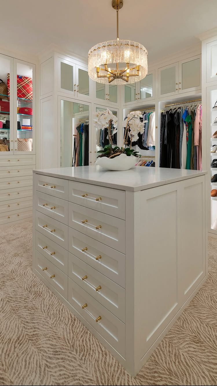 White walk-in closet with a central storage island and double-sided hanging racks.
