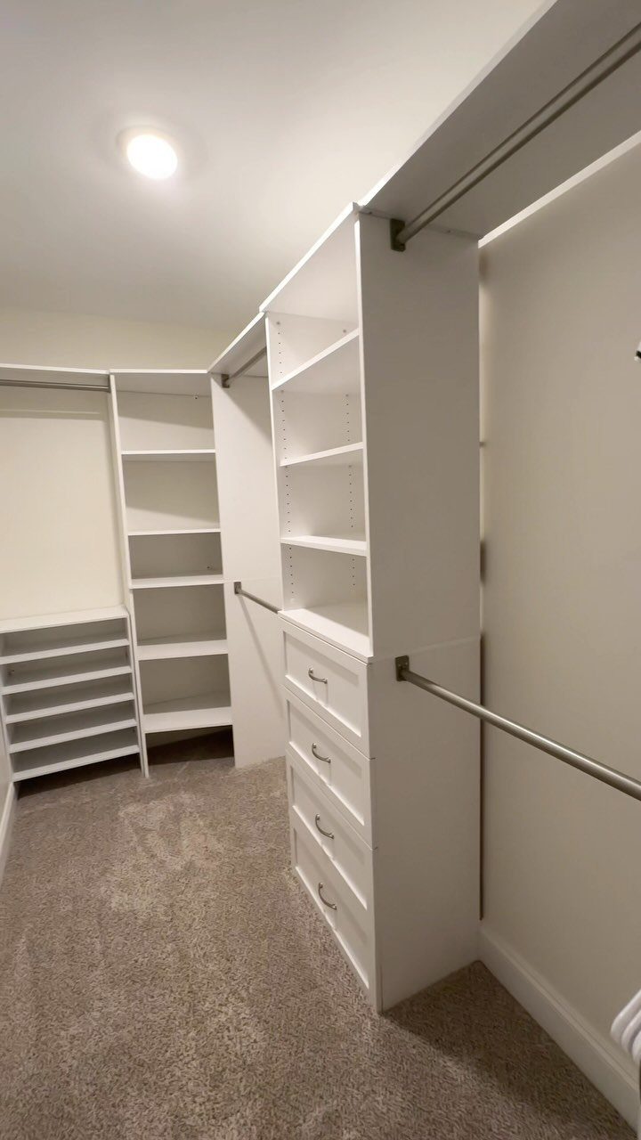 White walk-in closet with built-in shelves, drawers, and metal hanging rods.