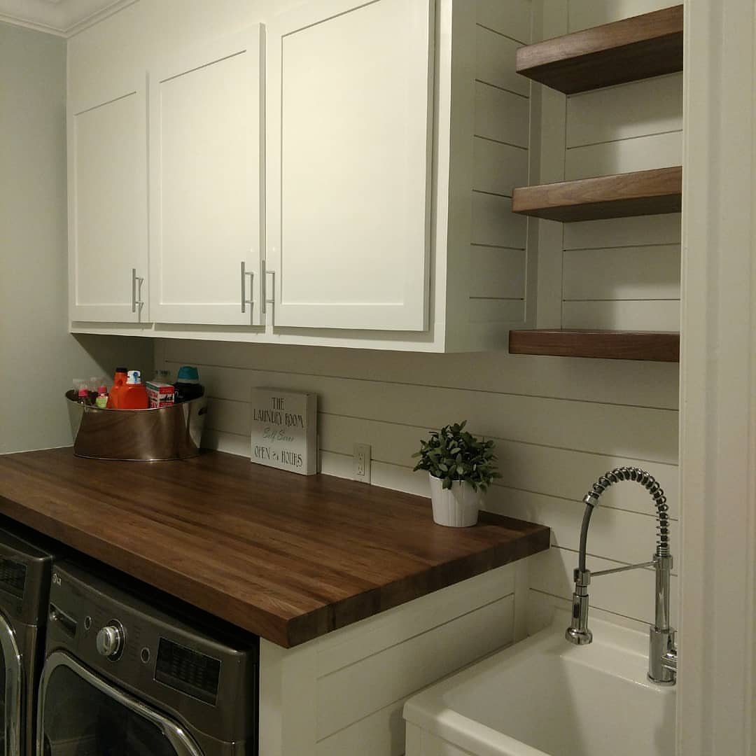 Dark wood butcher block countertop in a laundry room with white cabinets and sink
