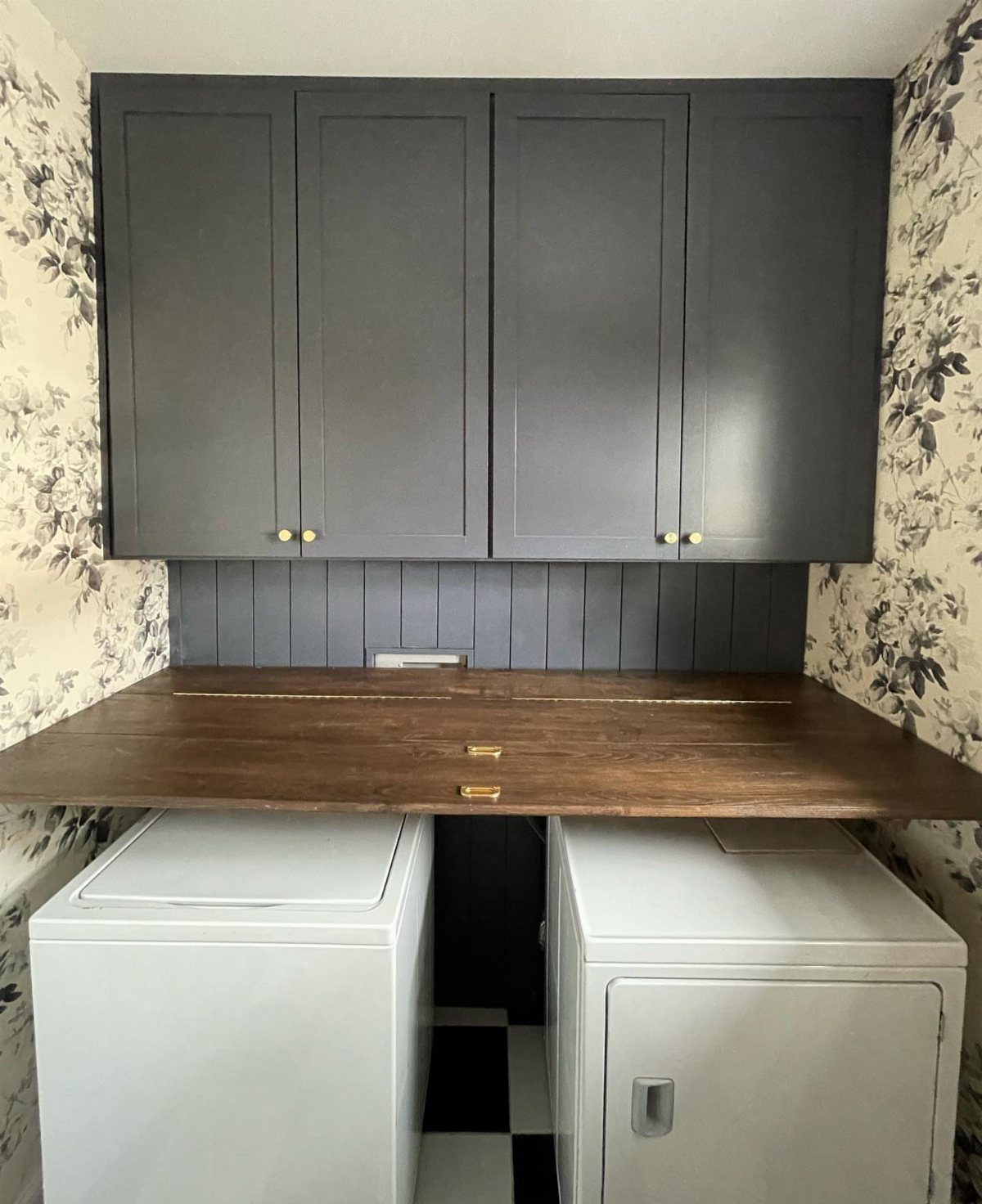 Wooden folding table surface installed between two white washing machines in a laundry room
