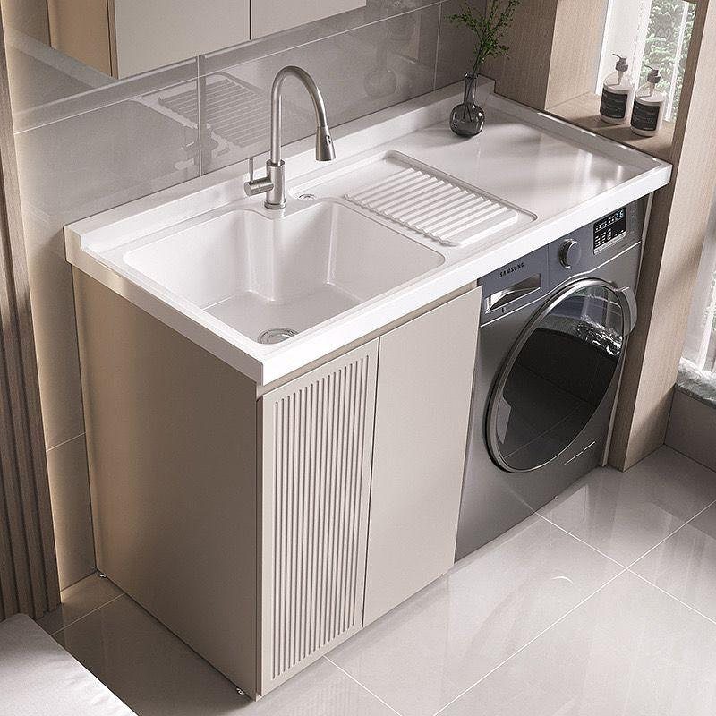White utility sink with chrome faucet next to a silver washing machine.