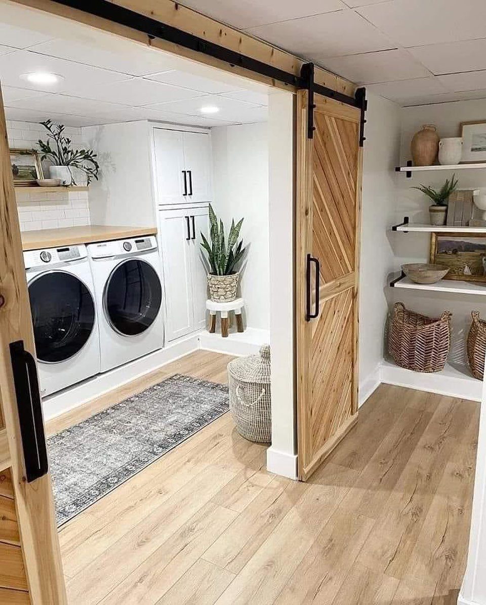 Basement laundry room with white appliances, wood countertops, and a sliding barn door.