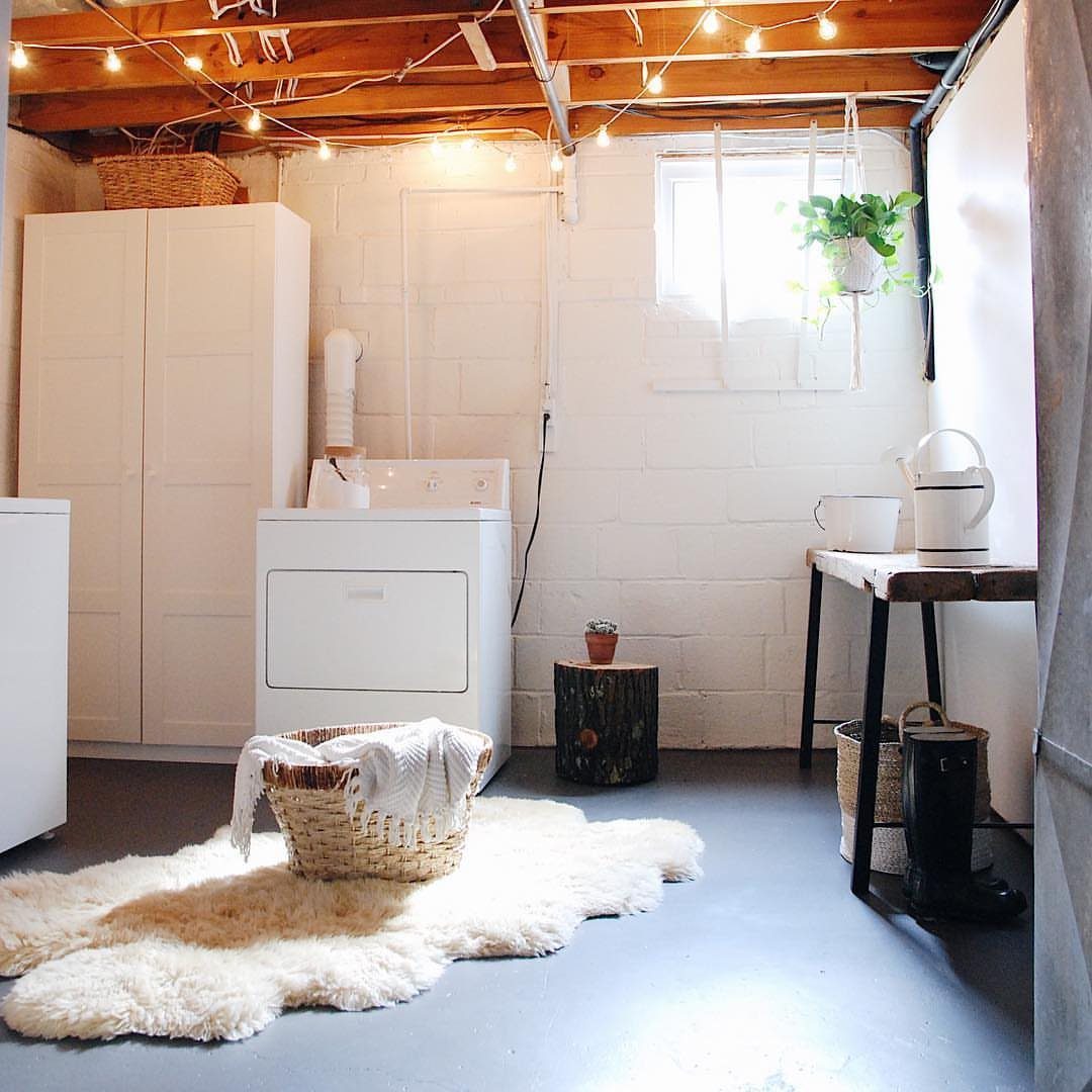 Basement laundry room with white brick walls, string lights, and white appliances.