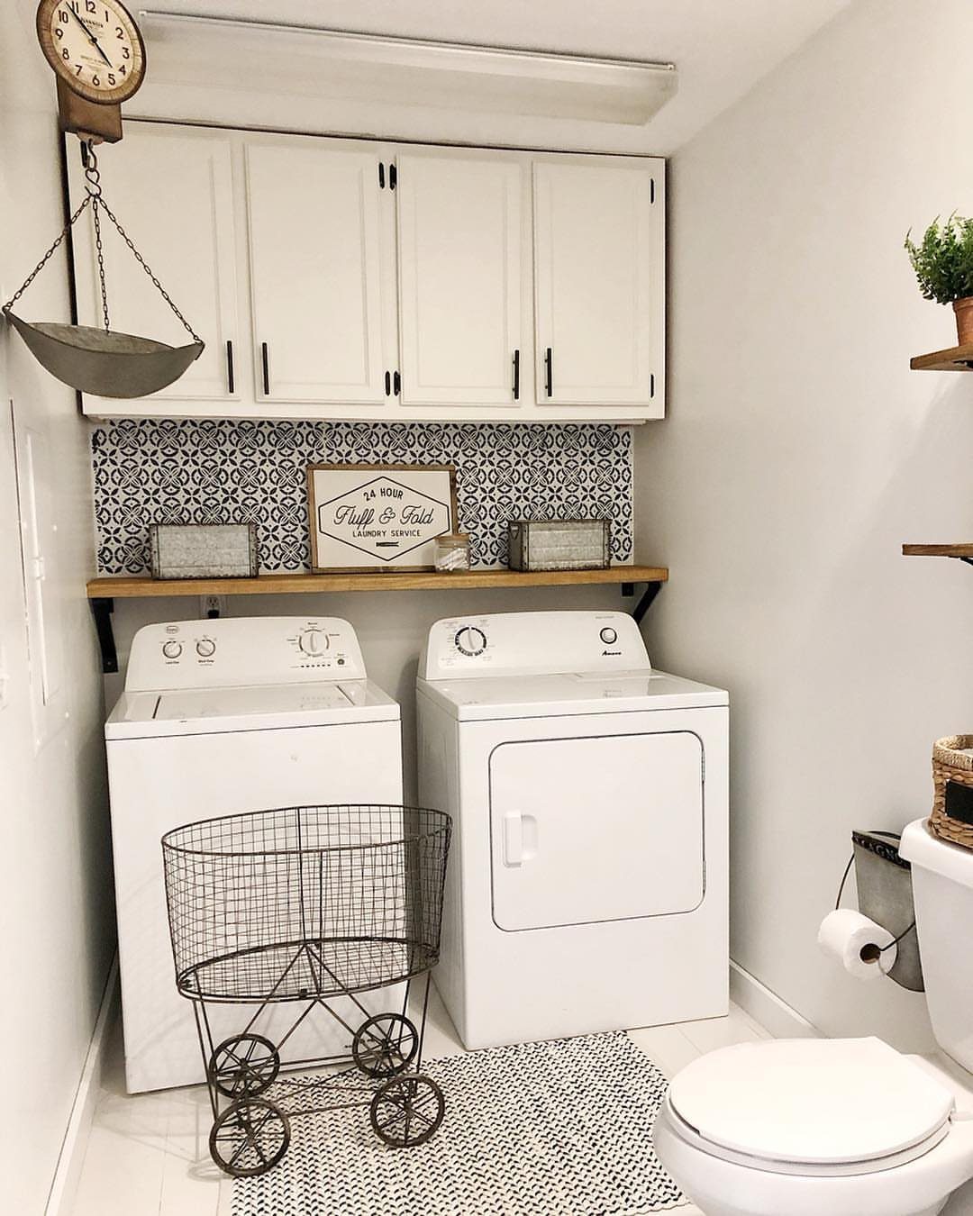 White washer and dryer with a patterned tile backsplash and wooden shelf.