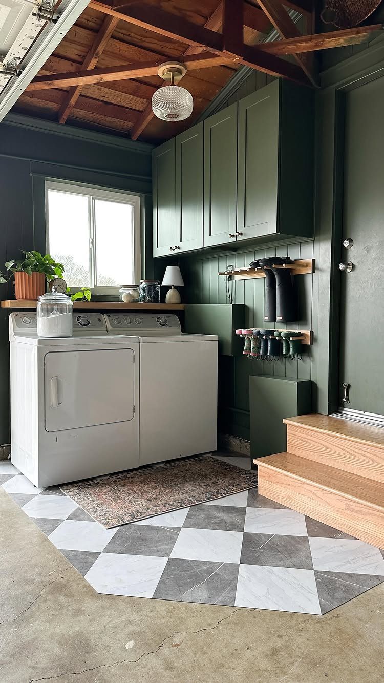 Laundry area in a garage with green cabinets, white appliances, and checkered flooring.