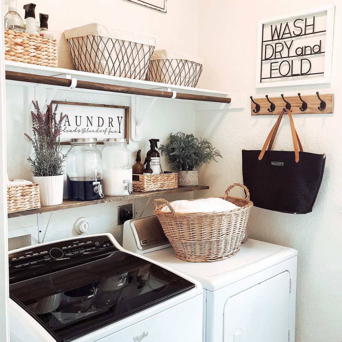 Laundry area with white machines, potted plants, and decorative laundry signs on wall