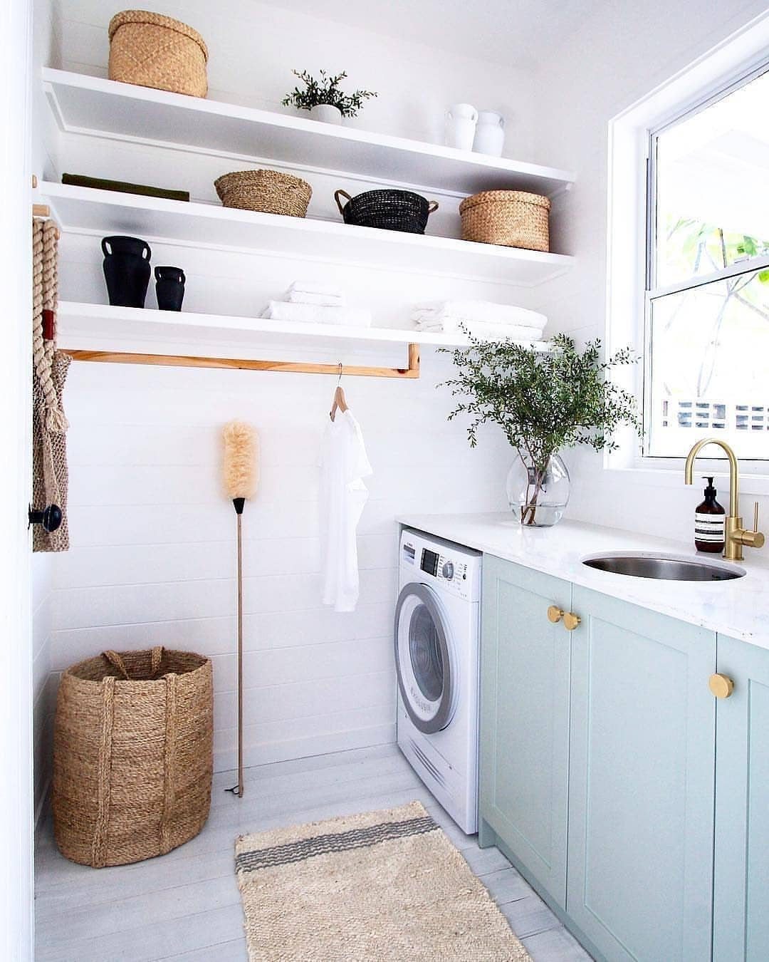 White open shelves with baskets above a light blue laundry room cabinet setup.