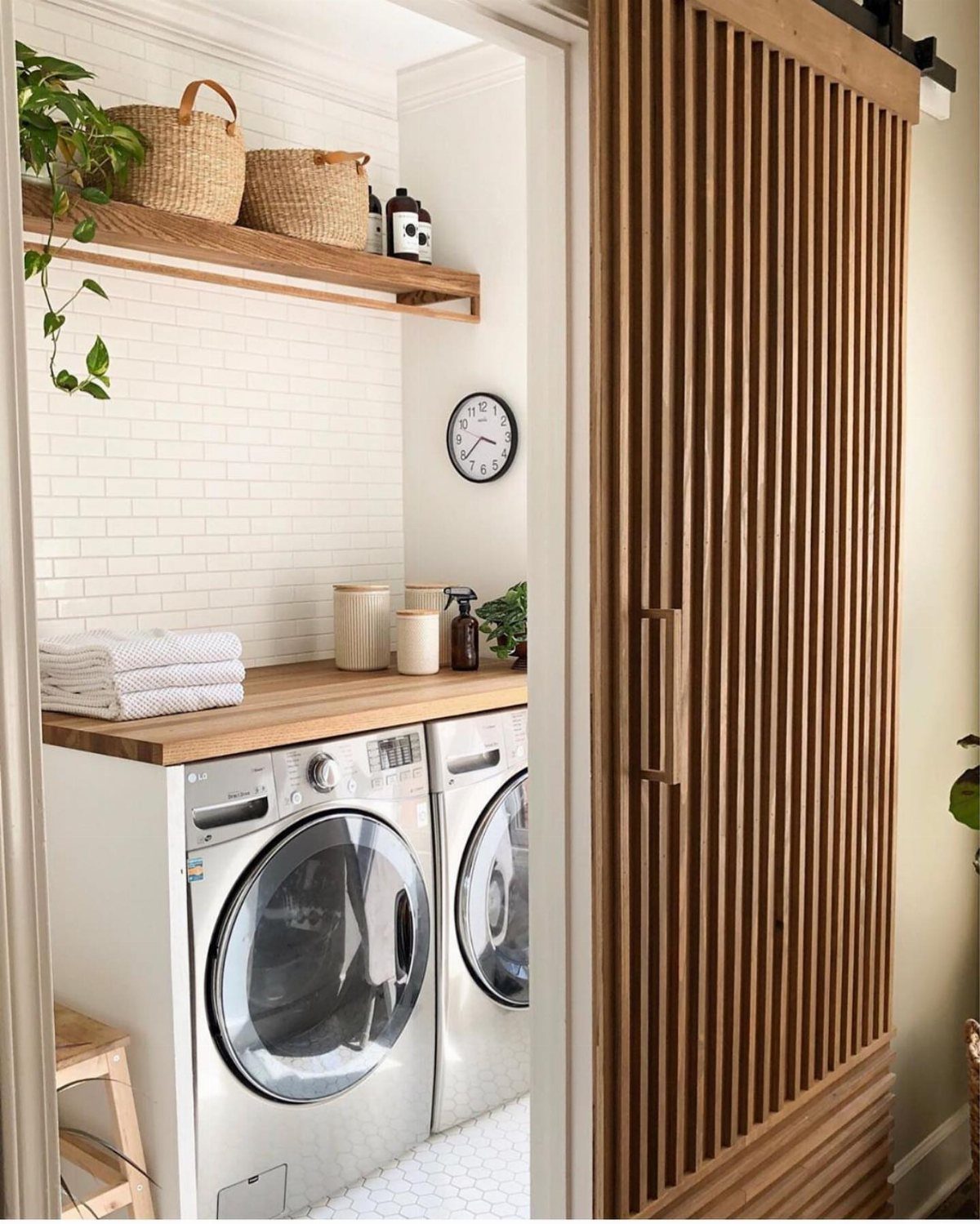 Wooden slatted sliding barn door opening to a white laundry room with appliances.