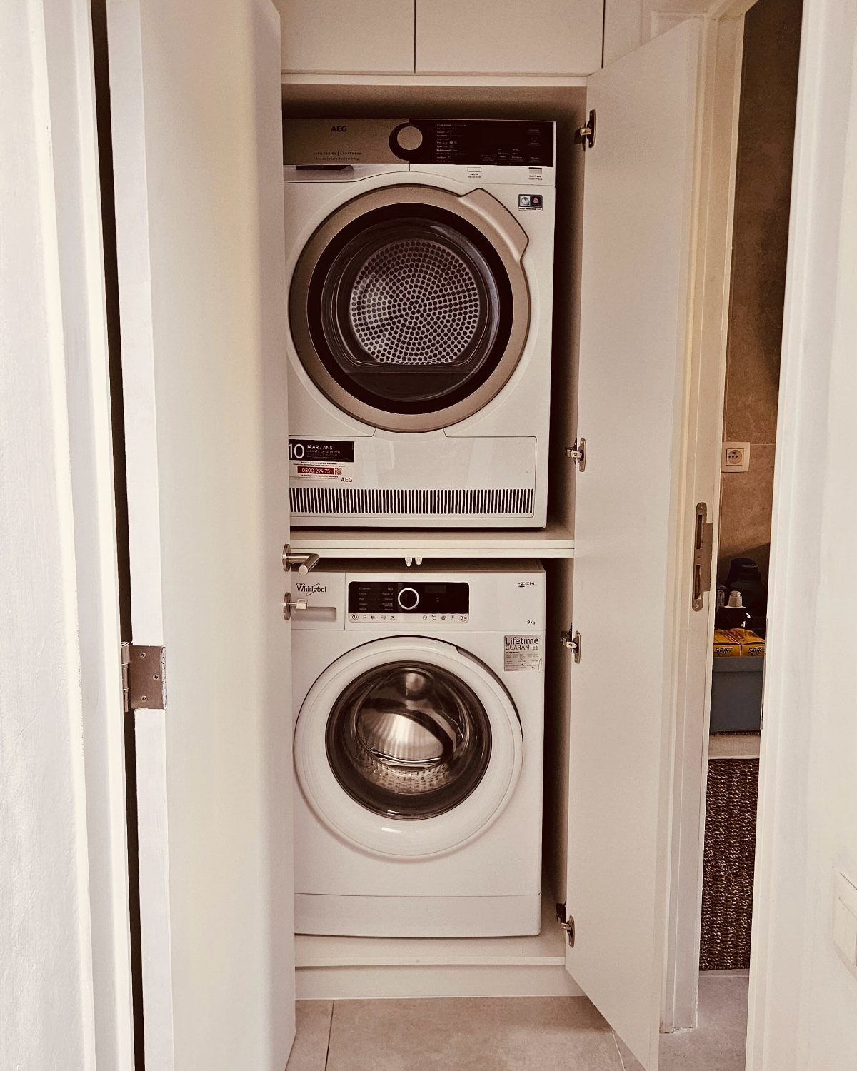 Stacked washer and dryer installed inside a white built-in laundry closet