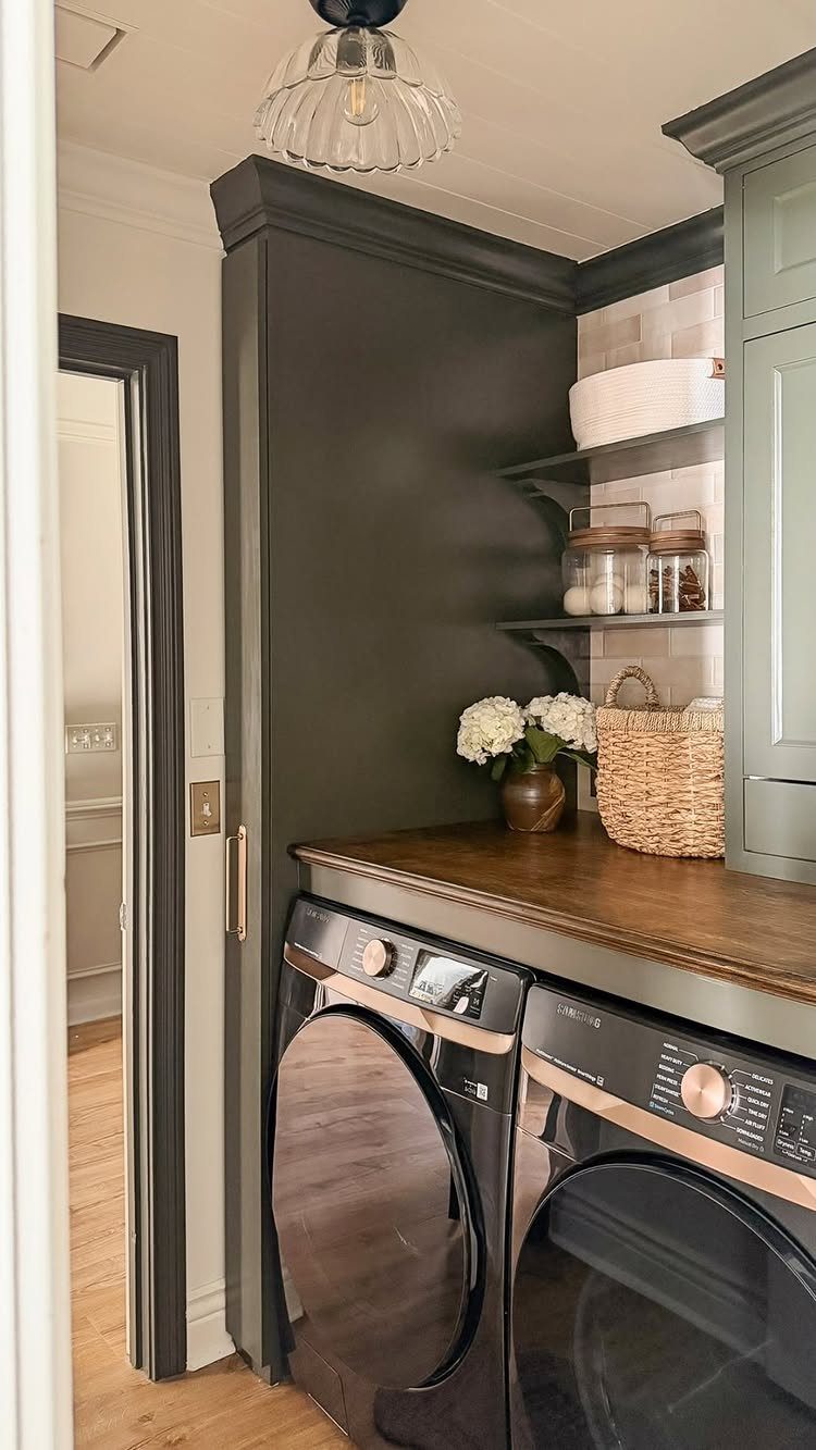 Wooden countertop installed over black front-loading washer and dryer in a small laundry room.