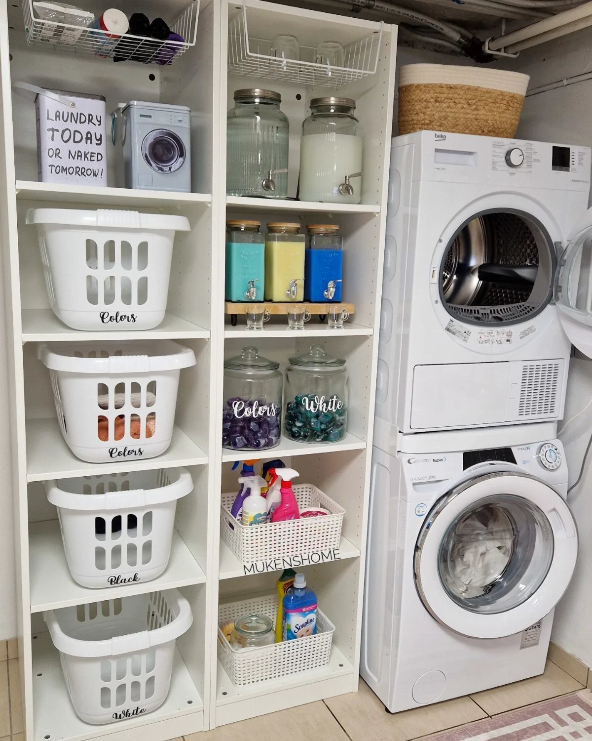 Stacked white washer and dryer next to shelves with matching white laundry baskets.
