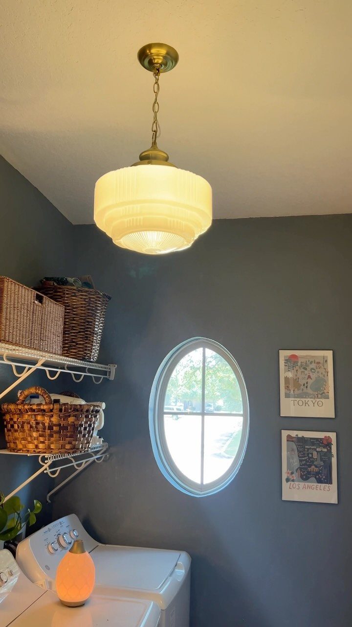 White top-loading washing machine in a blue laundry room with wicker baskets and oval window