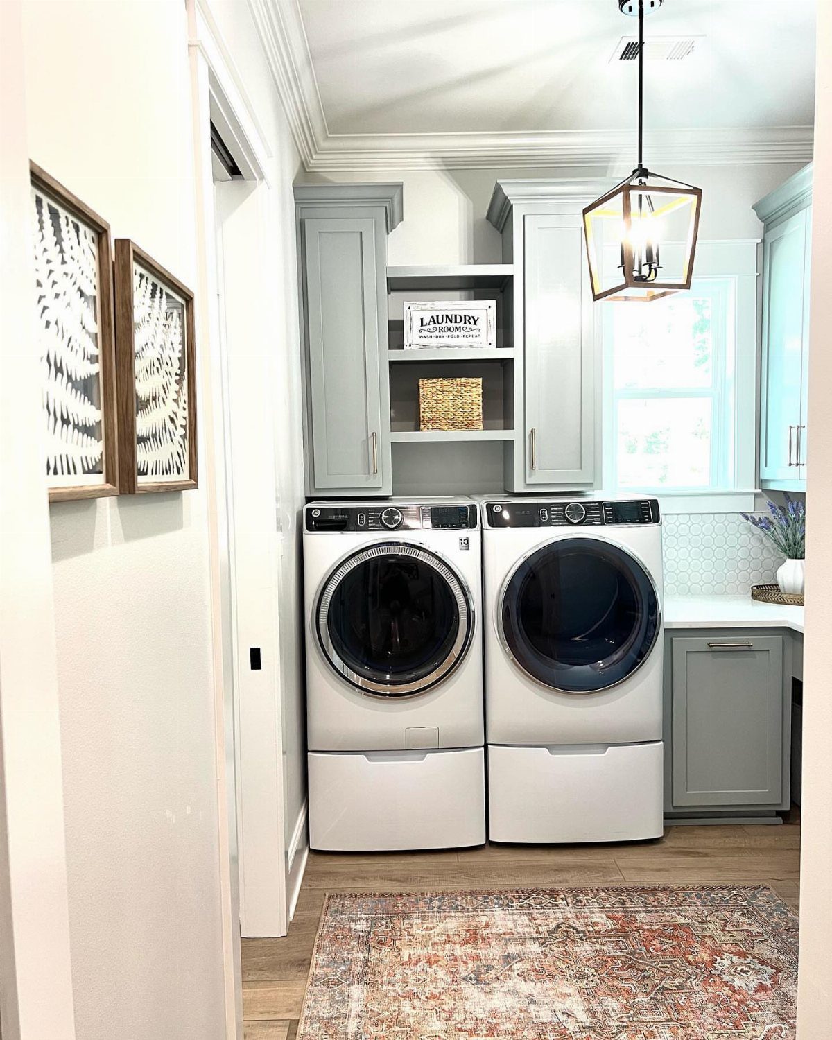 Lantern-style light fixture hanging in a laundry room with white appliances and grey cabinets.