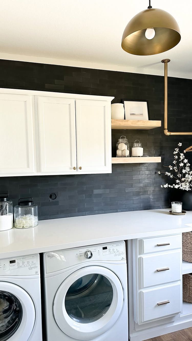 Gold dome pendant light hanging over white laundry room cabinets and appliances.