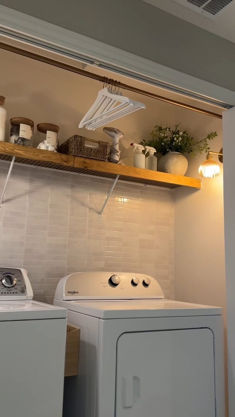 Small globe light fixture illuminating a wooden shelf above white laundry machines.