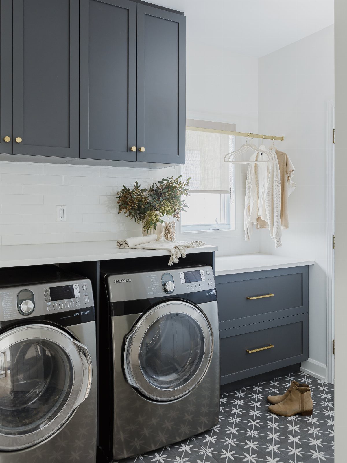 Laundry room with dark grey cabinets, white countertops, and front-loading washer and dryer.