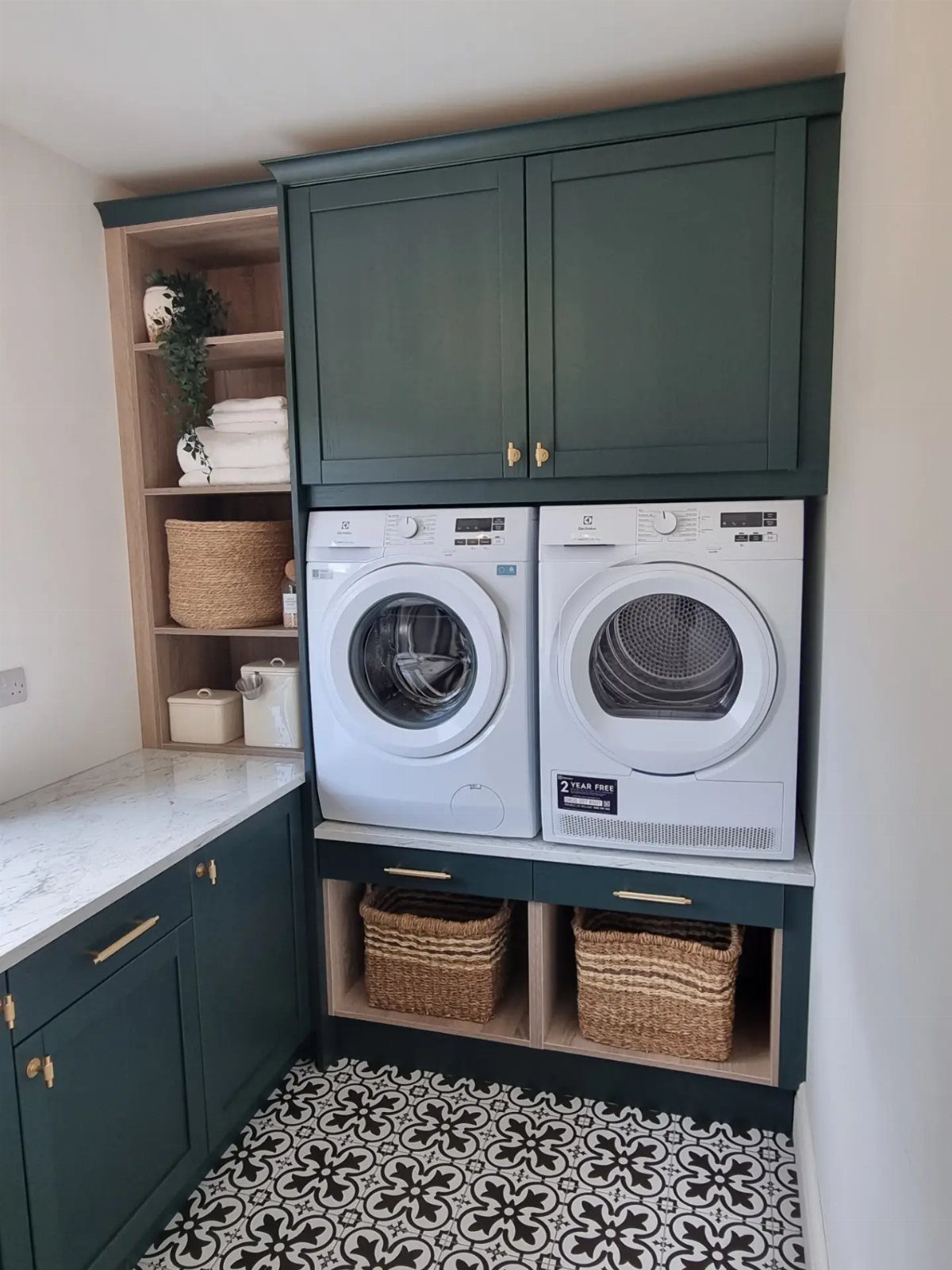 Laundry room with dark green cabinets, white appliances, and patterned tile flooring.