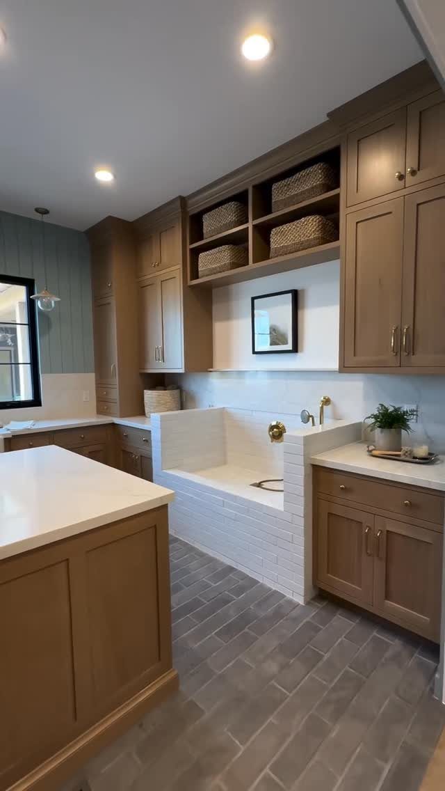 Elevated white tiled dog washing station built into brown mudroom cabinetry.