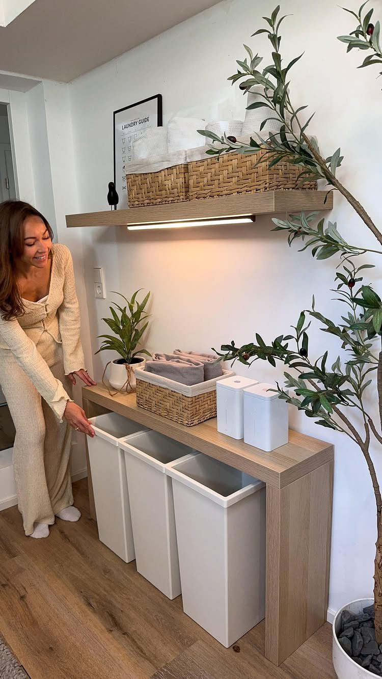 Woman standing by a light wood laundry station with white bins and shelving.