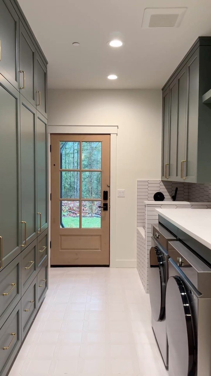 Laundry room and mudroom with grey cabinets, white counters, and a glass door.