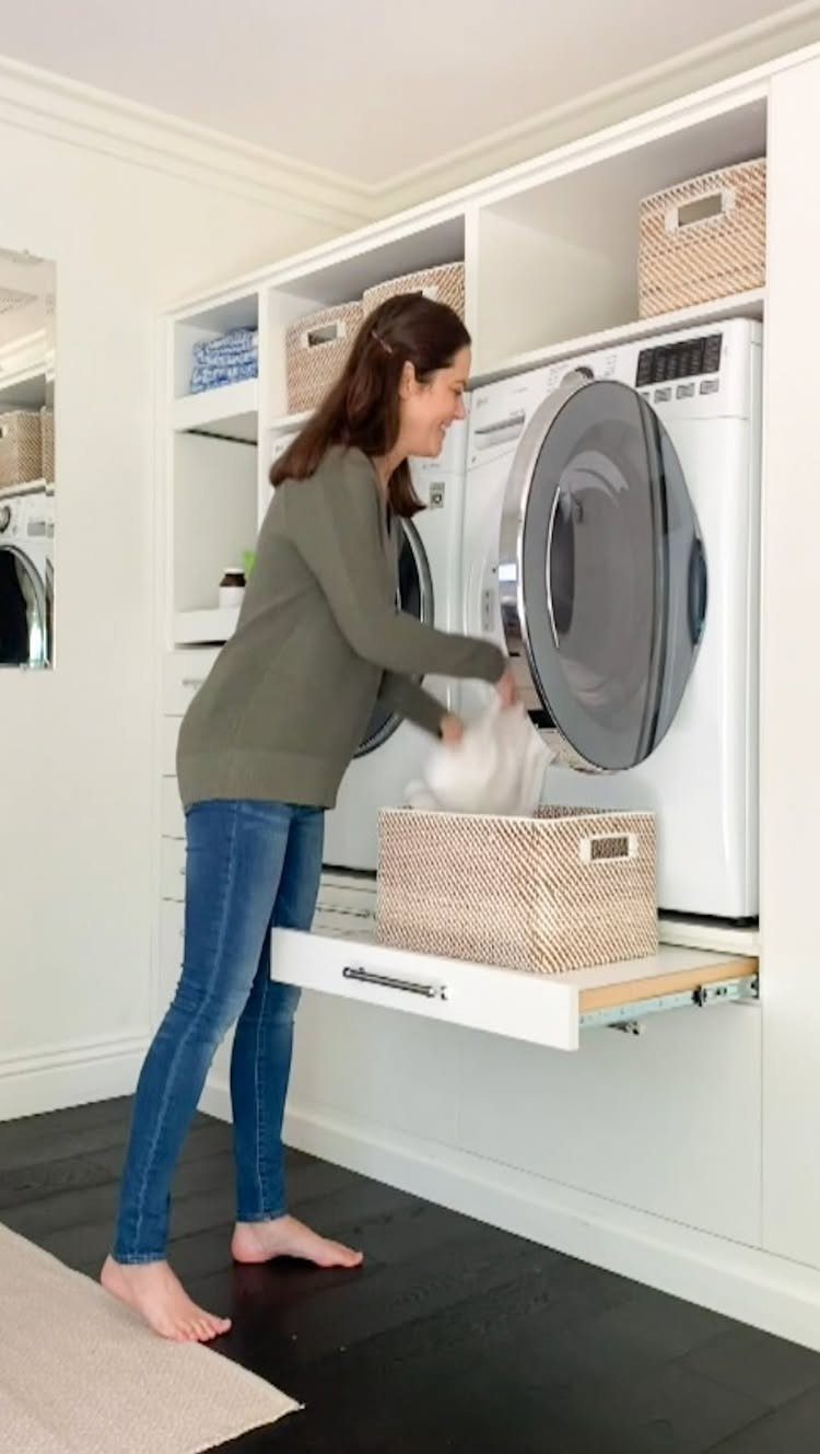 Woman using a pull-out laundry storage drawer next to a white dryer.