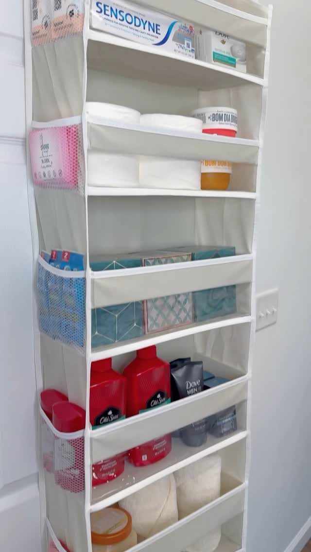 White fabric over-the-door organizer filled with toiletries and personal care products.