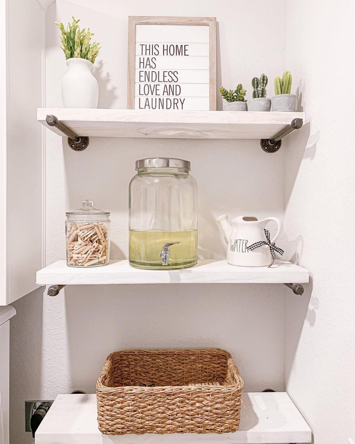 White floating shelves with metal brackets holding laundry supplies and decorative items.