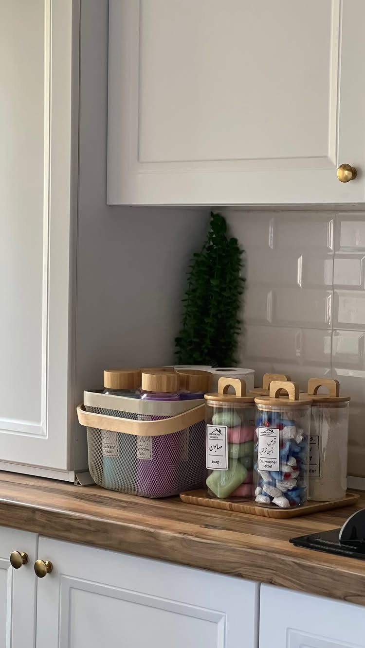 Glass jars with wooden lids holding laundry pods on a wooden countertop.