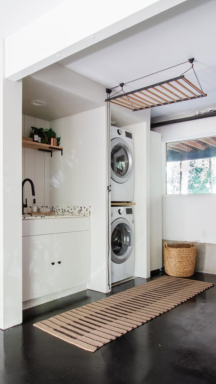 Wooden hanging rack suspended from the ceiling in a modern white laundry room.