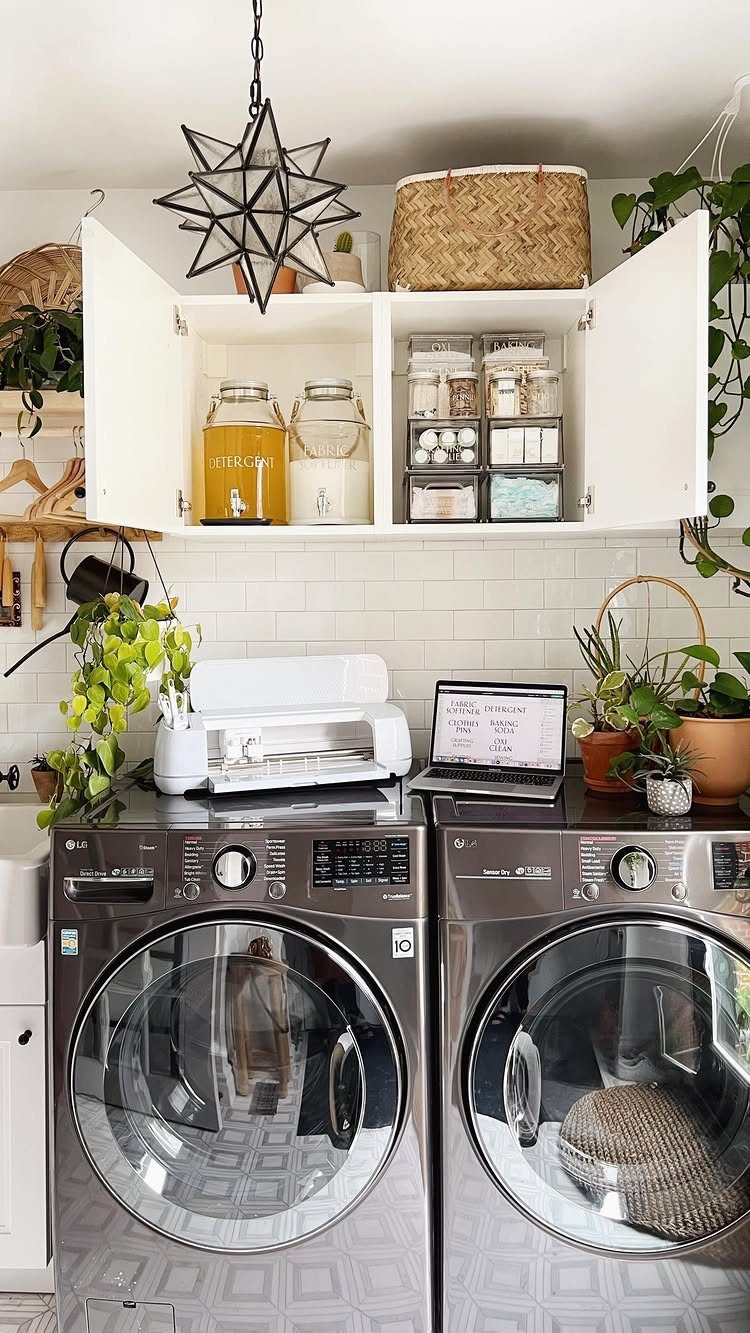 Grey laundry machines with white overhead cabinets containing labeled glass jars and bins.