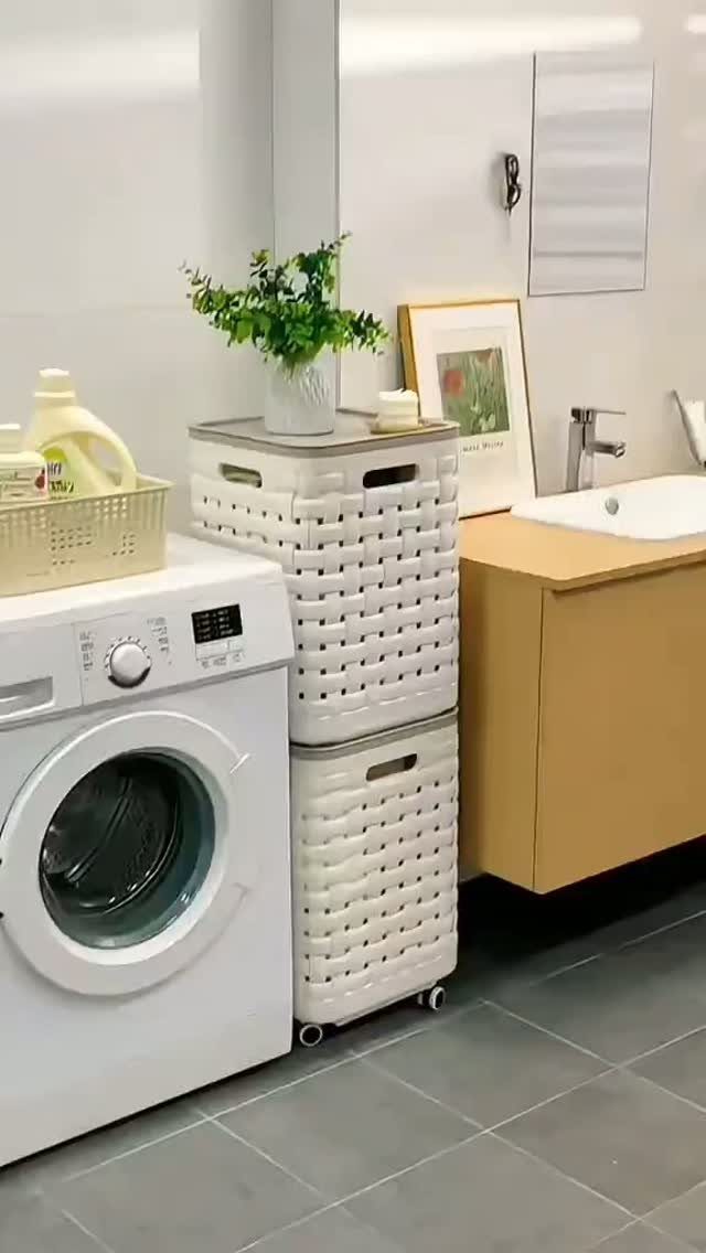 White washing machine next to stacked white plastic laundry baskets on wheels.