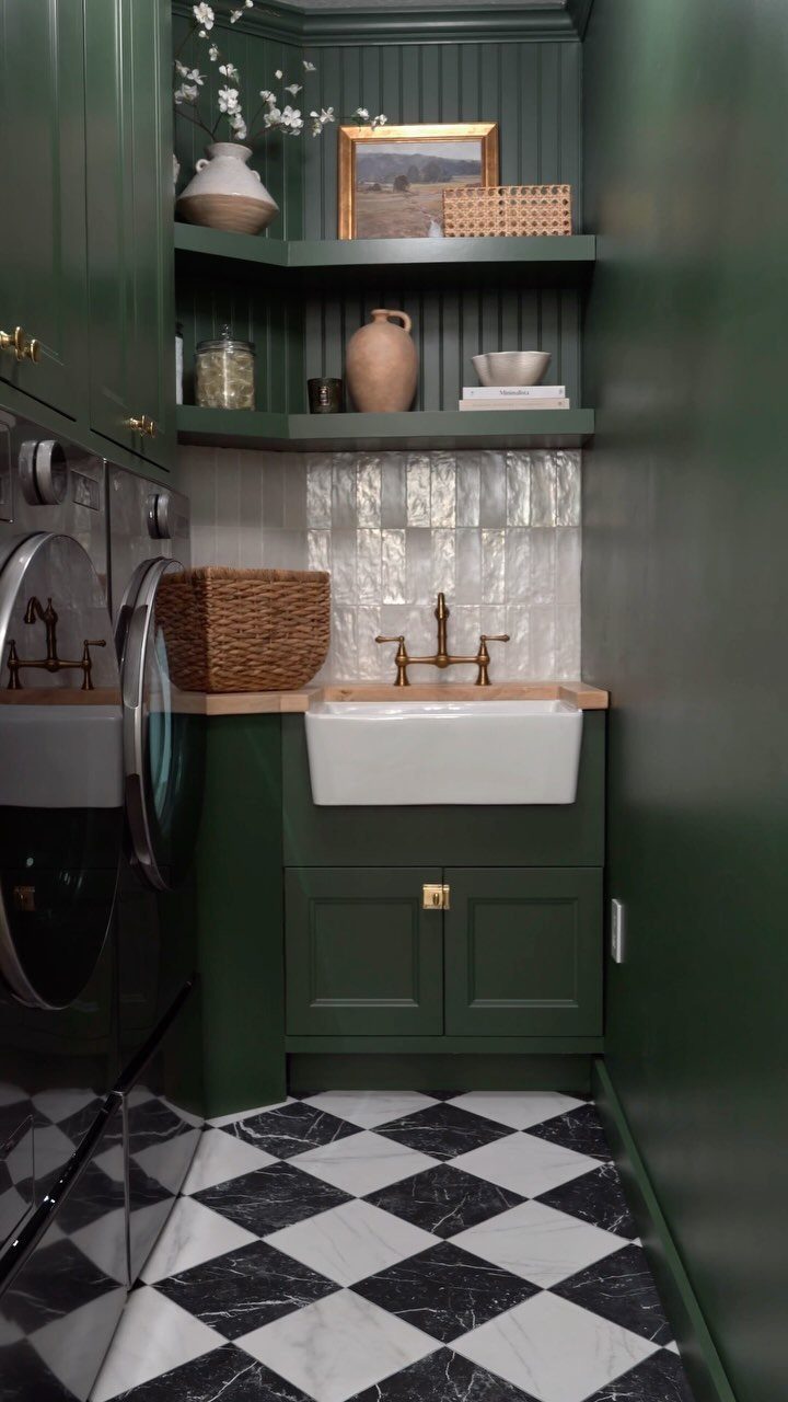 Dark green laundry room with white farmhouse sink and checkered floor tiles.
