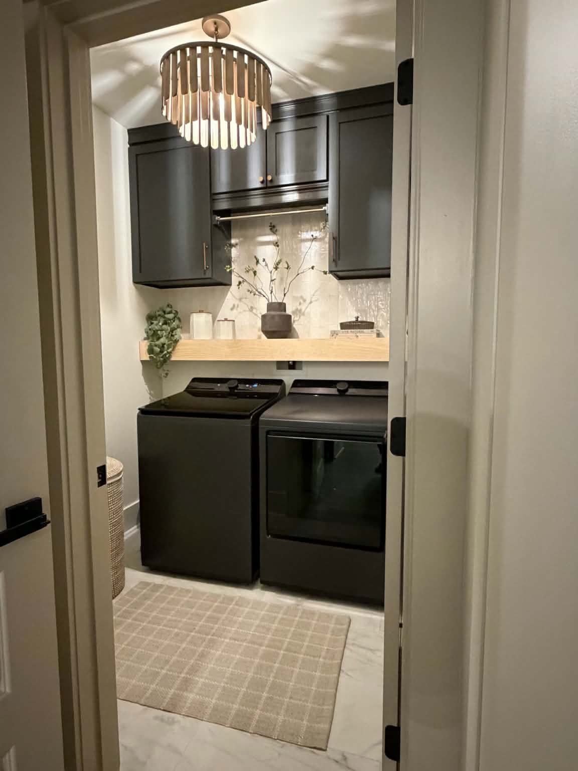 Laundry room with dark gray cabinets, black appliances, and light gray walls.