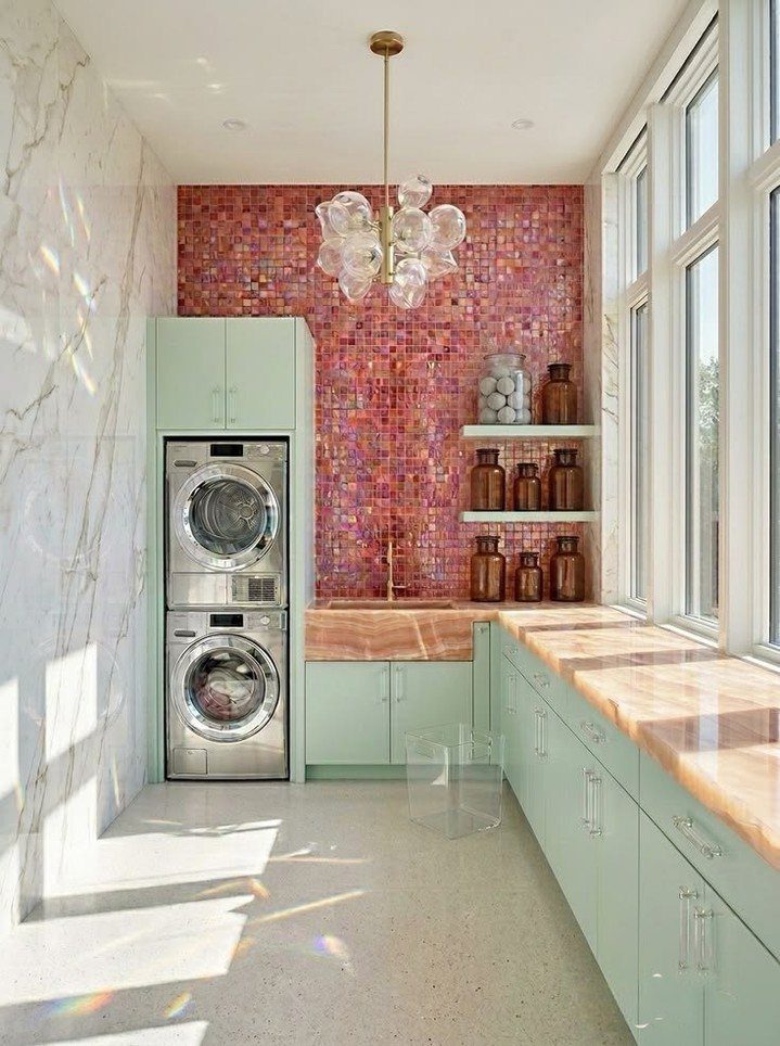 Laundry room with mint green cabinets and a pink mosaic tile backsplash.