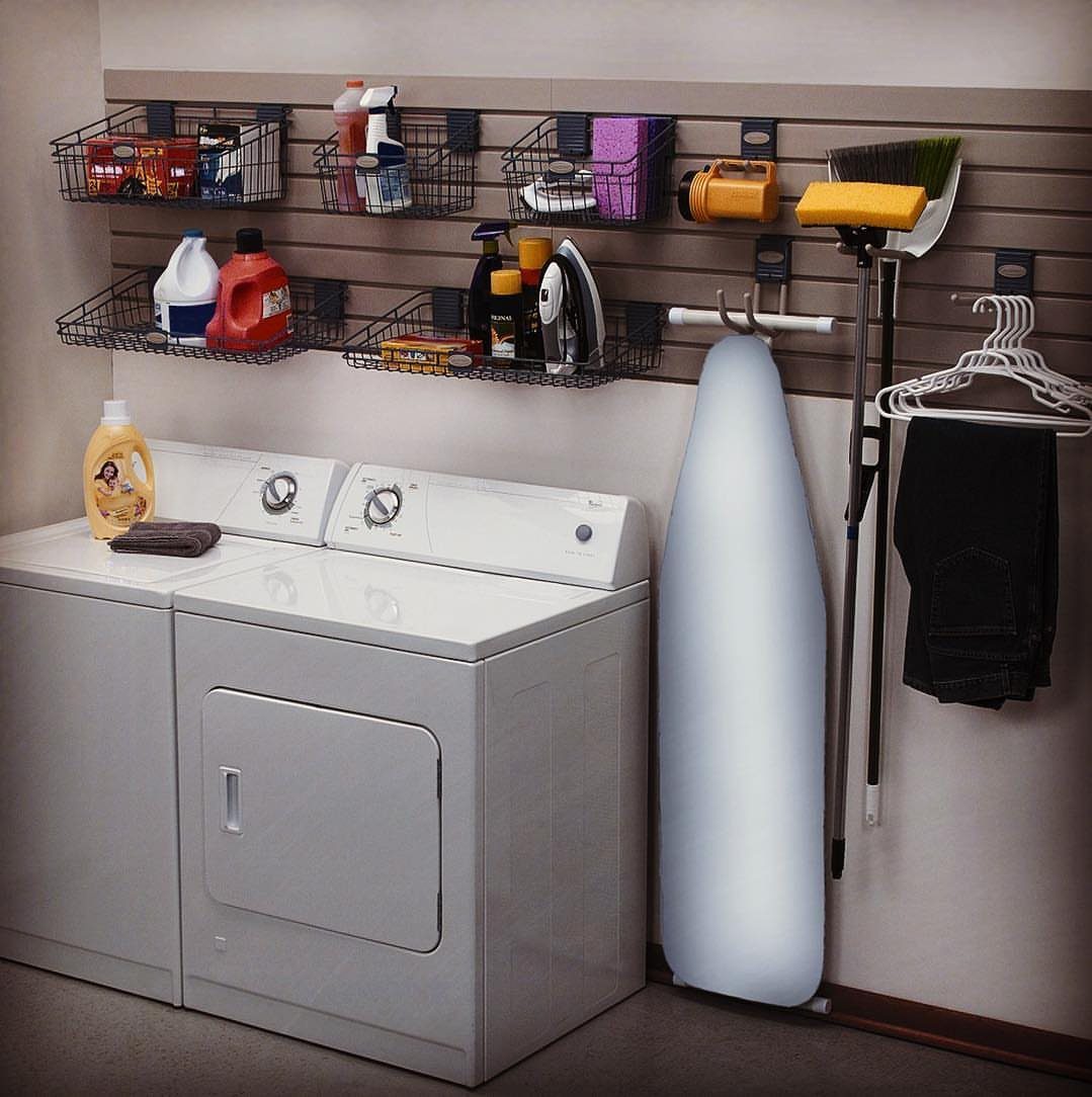 Slatwall system with adjustable wire baskets and hanging rod above white laundry machines.