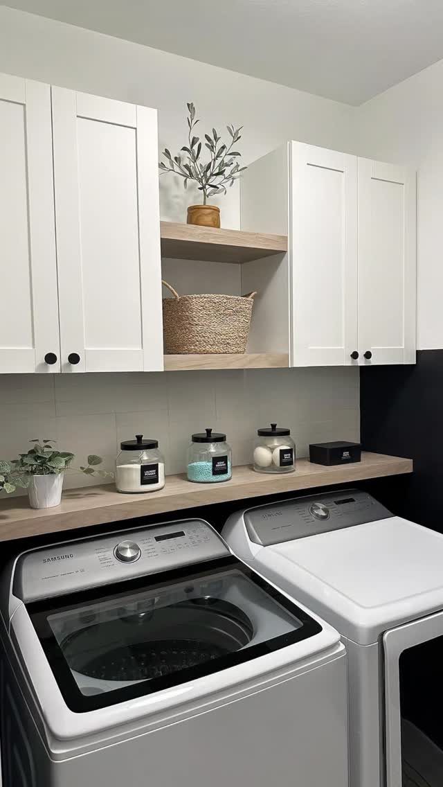 Wooden floating shelves in a laundry room holding glass jars and woven baskets.