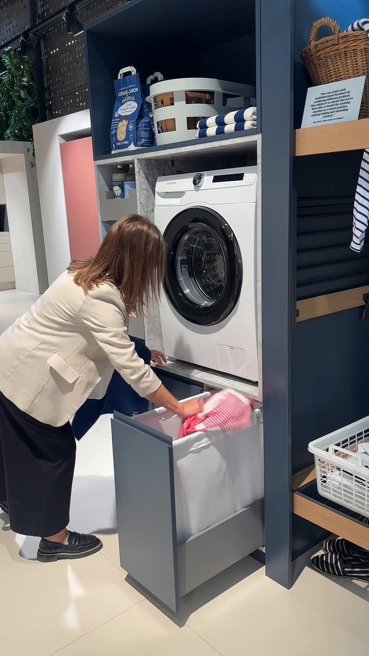 Woman pulling out a laundry hamper drawer from a blue shelving unit.