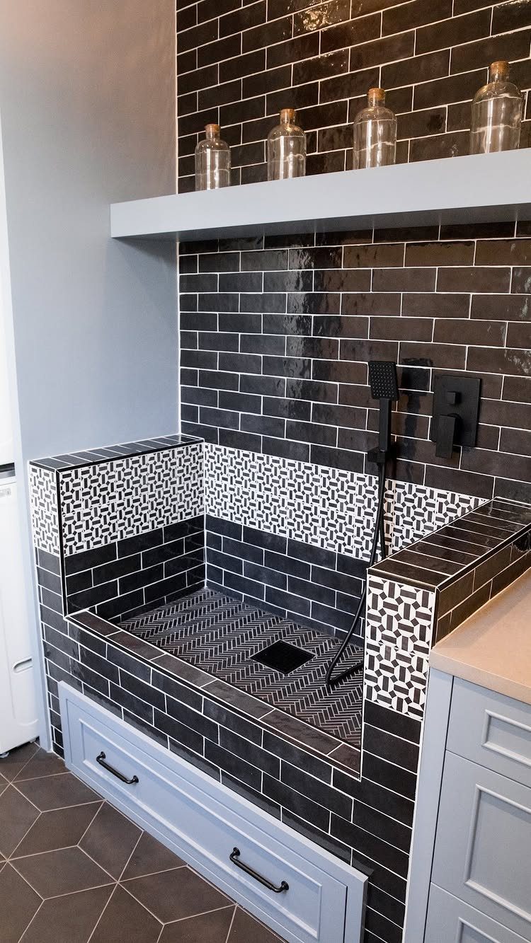 Built-in pet washing station with black subway tiles and handheld shower sprayer.