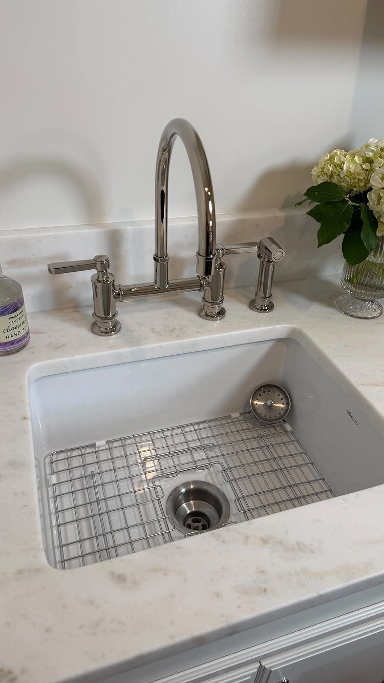 White undermount utility sink with chrome faucet installed in a marble countertop.