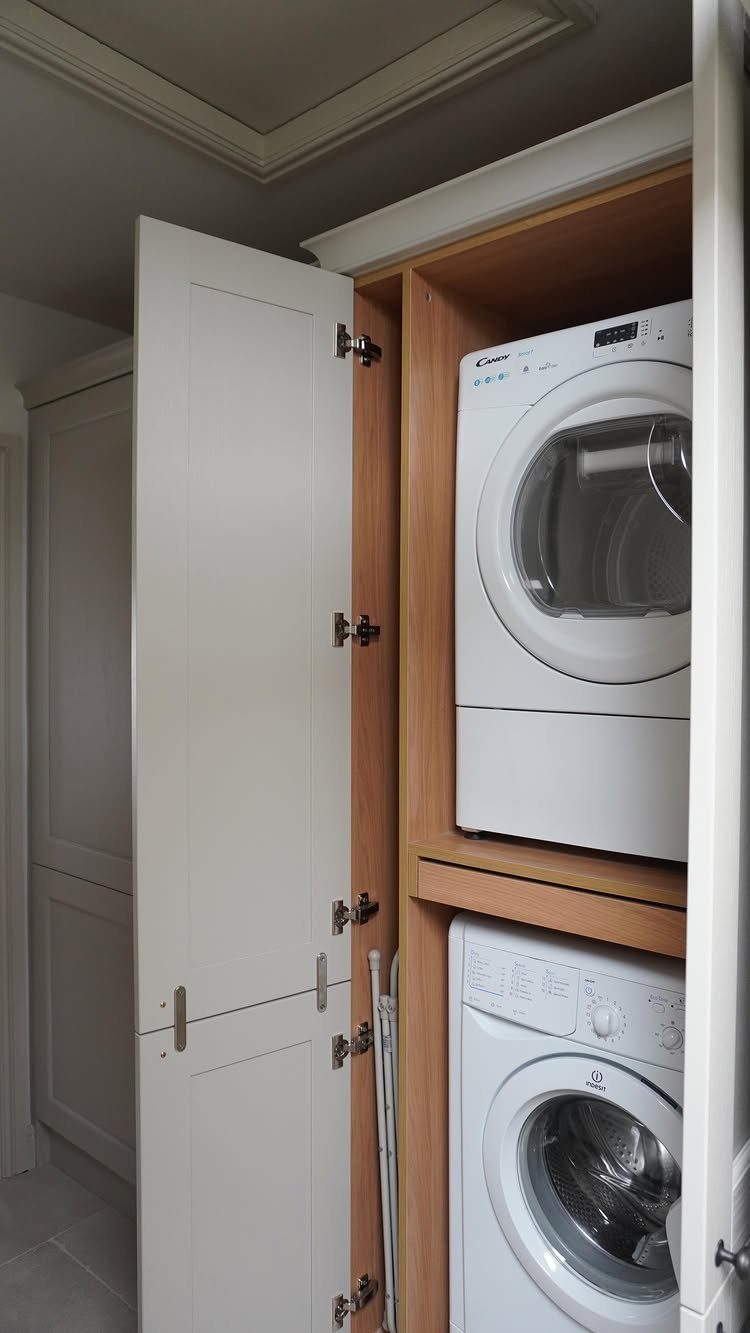White cabinetry enclosing a stacked washer and dryer in a laundry room
