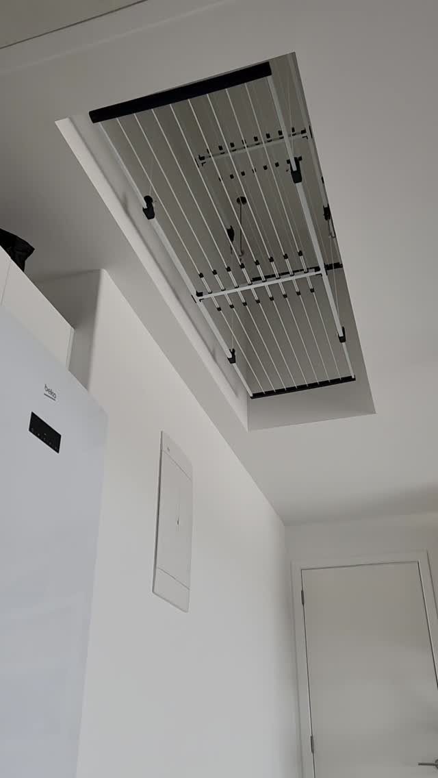 Ceiling-mounted retractable drying rack installed in a bright white laundry utility room.