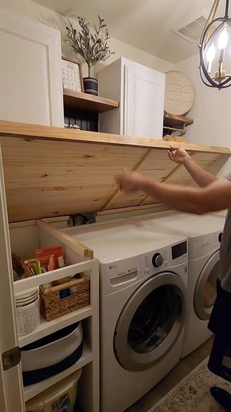 Wooden folding table extending over white front-loading washer and dryer in laundry room