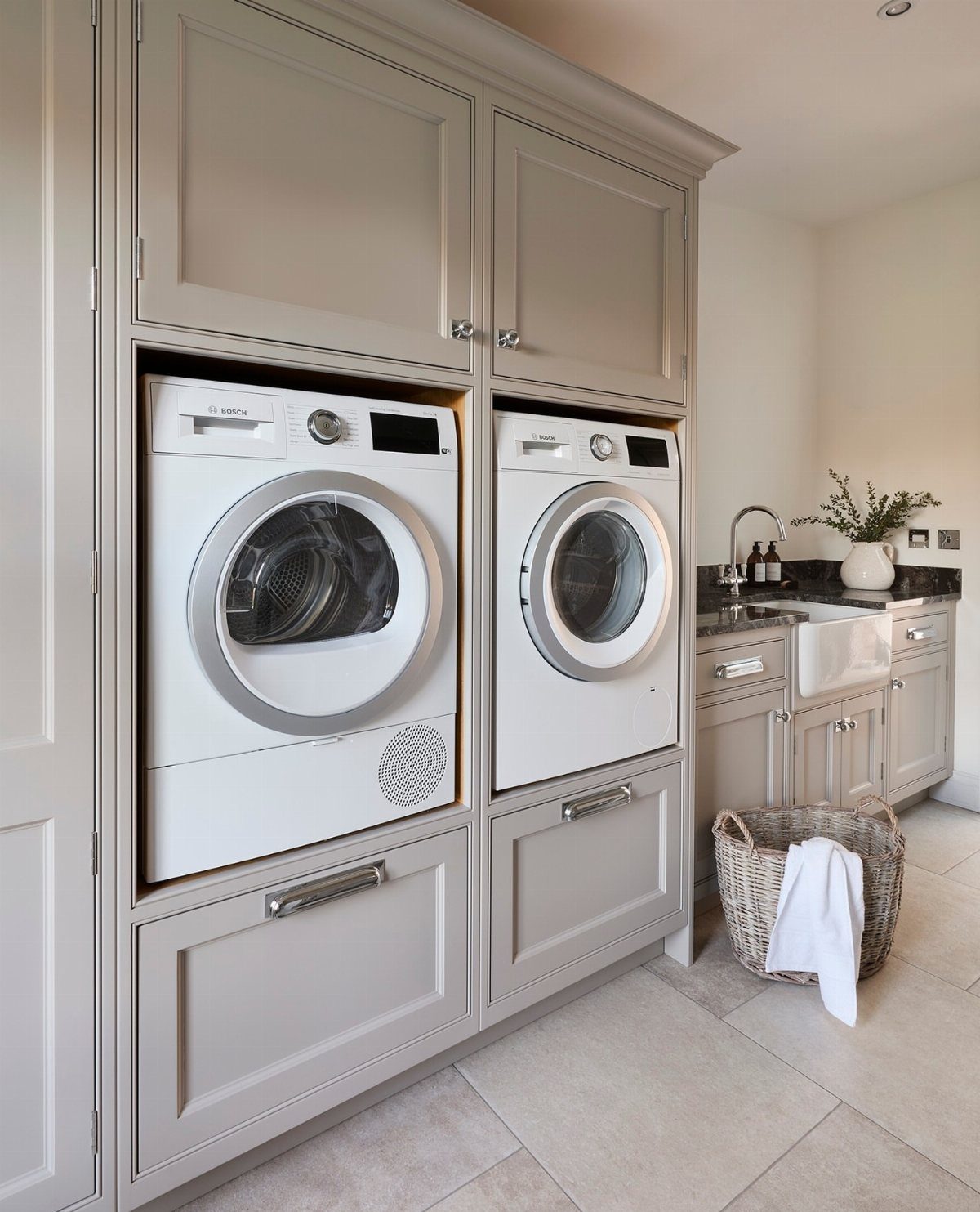 Grey laundry room cabinetry with built-in washer and dryer and deep storage drawers.
