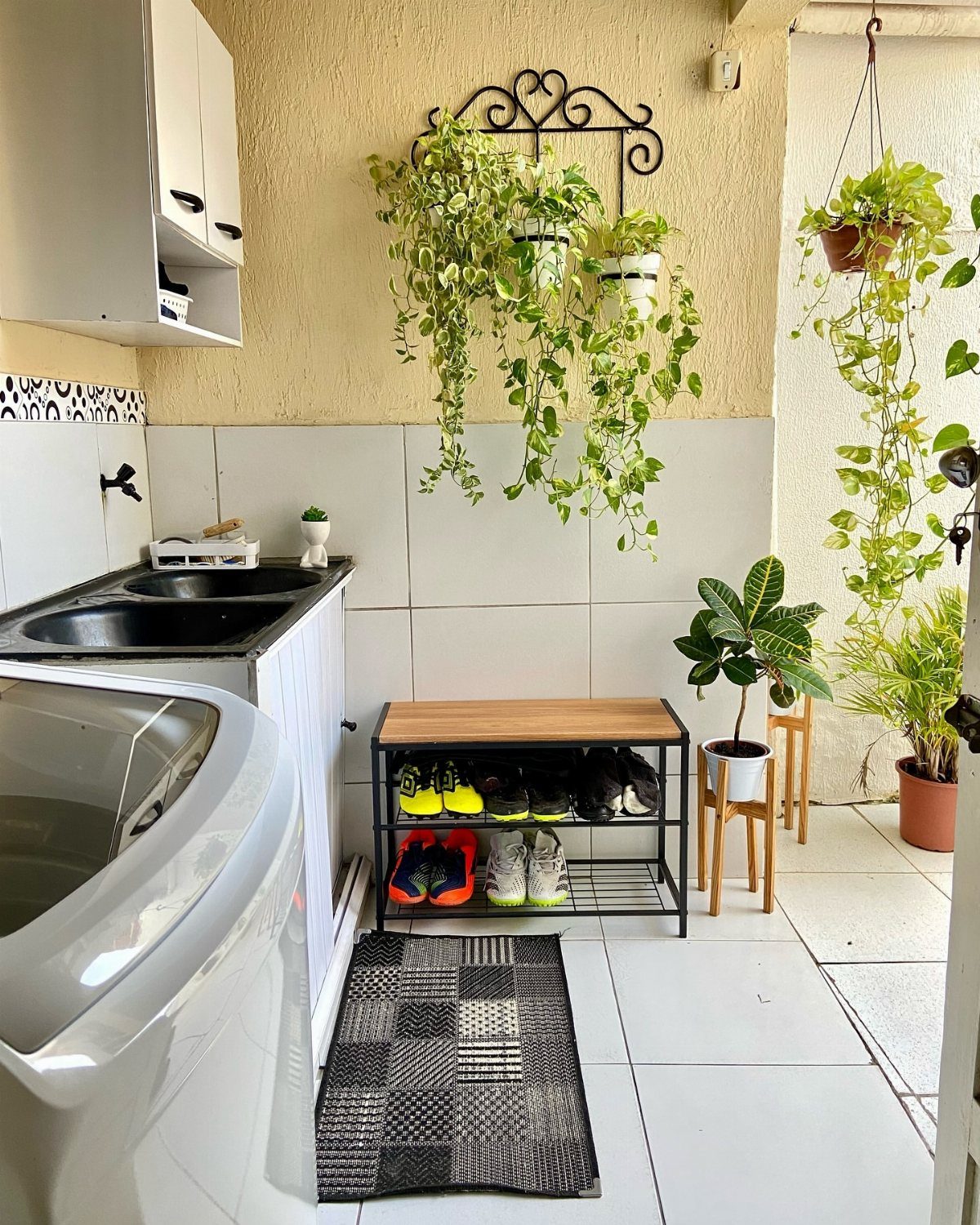 Laundry room with hanging trailing plants and potted greenery near a shoe rack.