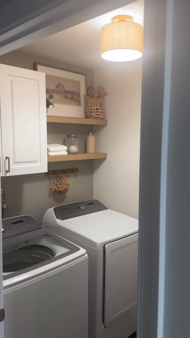 Pendant light illuminating a laundry room with white machines and wooden shelves.