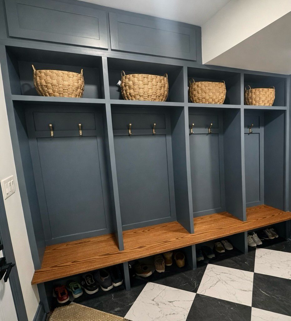 Blue built-in mudroom unit with wooden benches, hooks, and wicker basket cubbies.