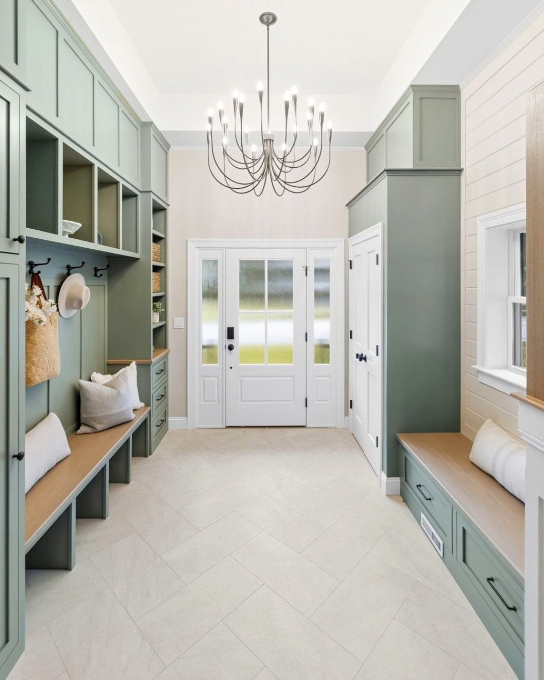 Sage green mudroom built-ins with a wooden open bottom bench and upper cubbies.