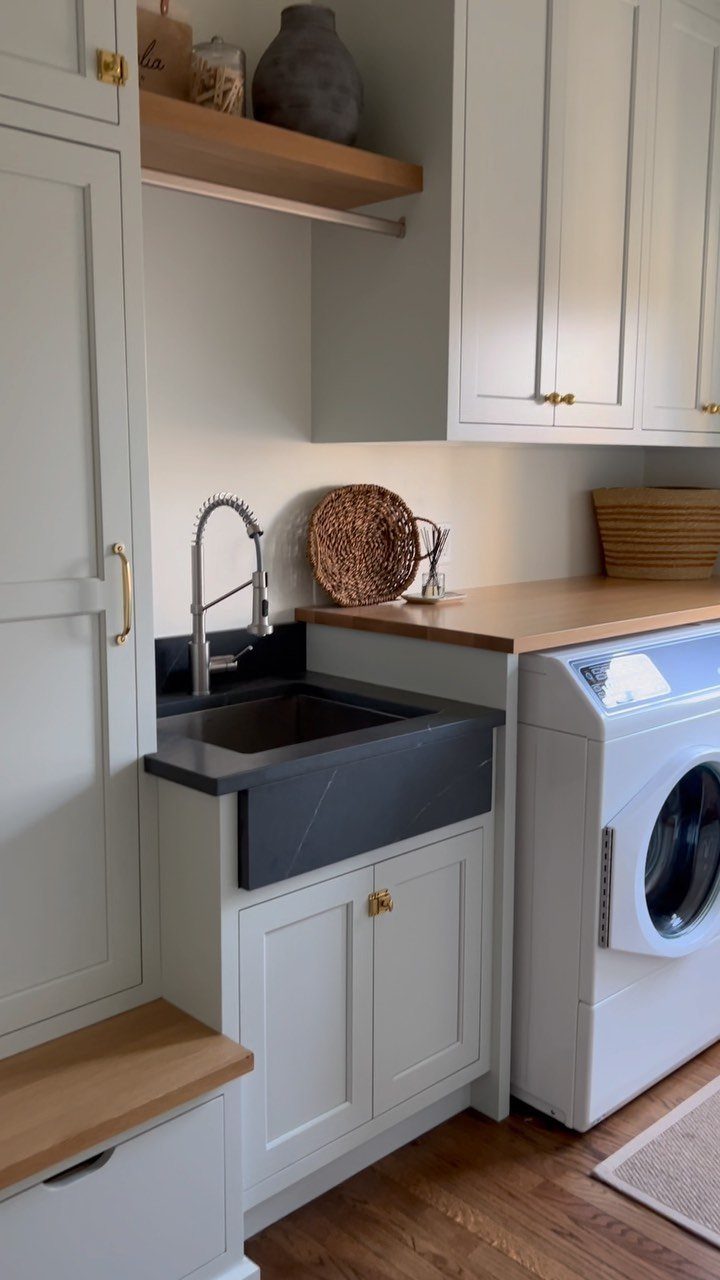 Dark grey apron-front utility sink with chrome faucet in light grey cabinetry.