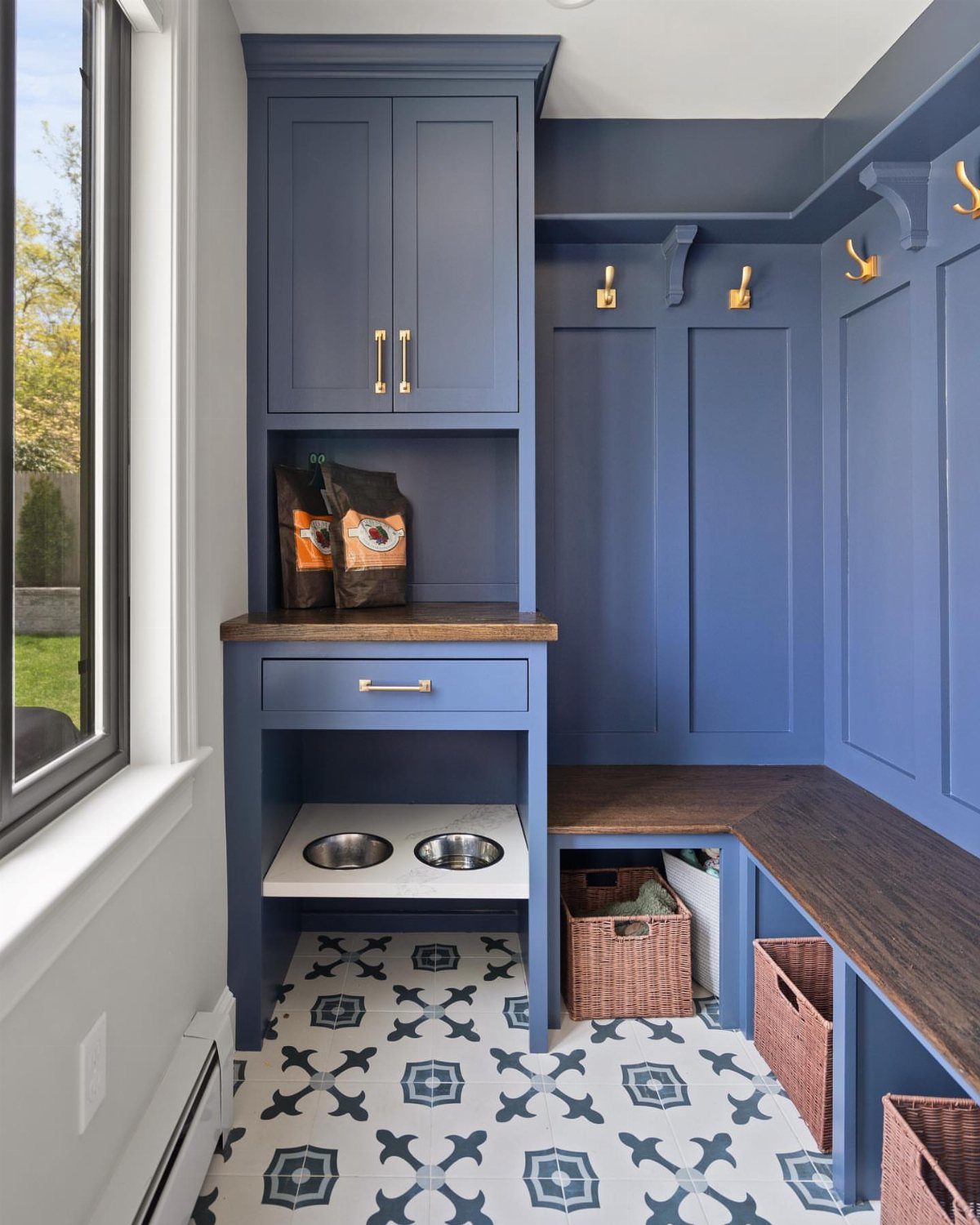 Blue mudroom with built-in cabinets, wooden bench, and patterned blue and white tiles.