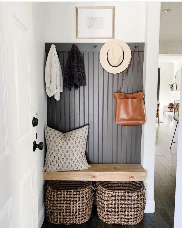 Mudroom nook with grey slatted wall, wooden bench, and woven storage baskets.
